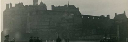 View of Edinburgh Castle, in black and white, with some people walking in the foreground