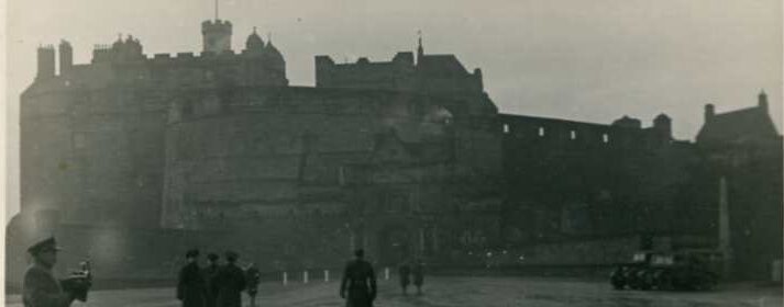 View of Edinburgh Castle, in black and white, with some people walking in the foreground