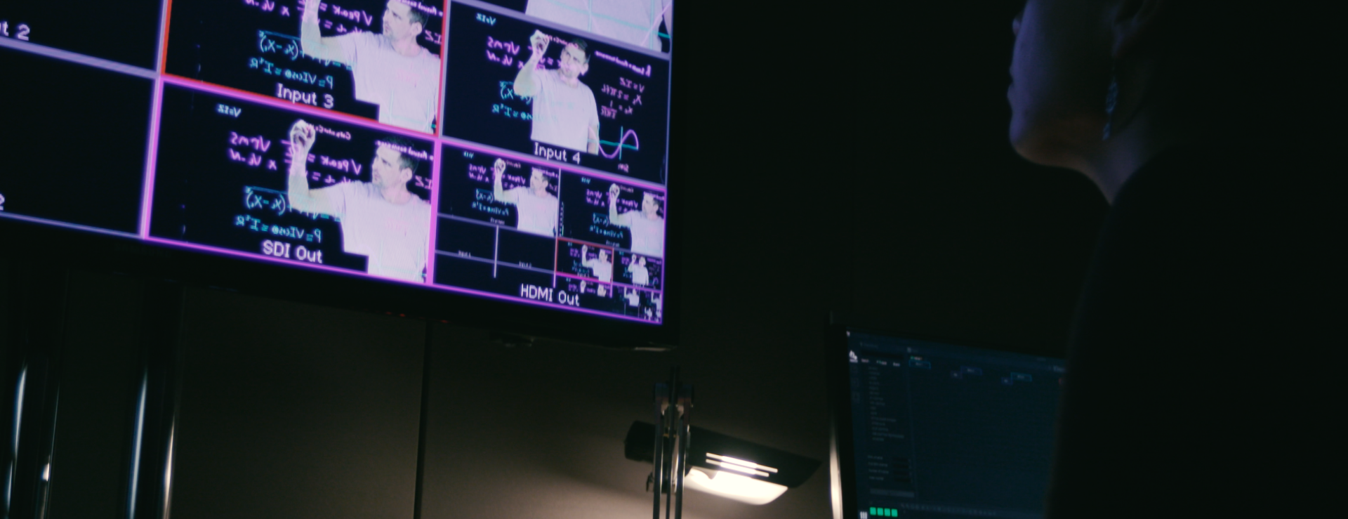 Photograph of a dark media studio with illuminated screens.