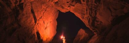 Person holding lamp inside cave