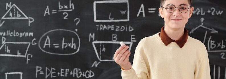 Young person holding chalk in front of a board covered in math