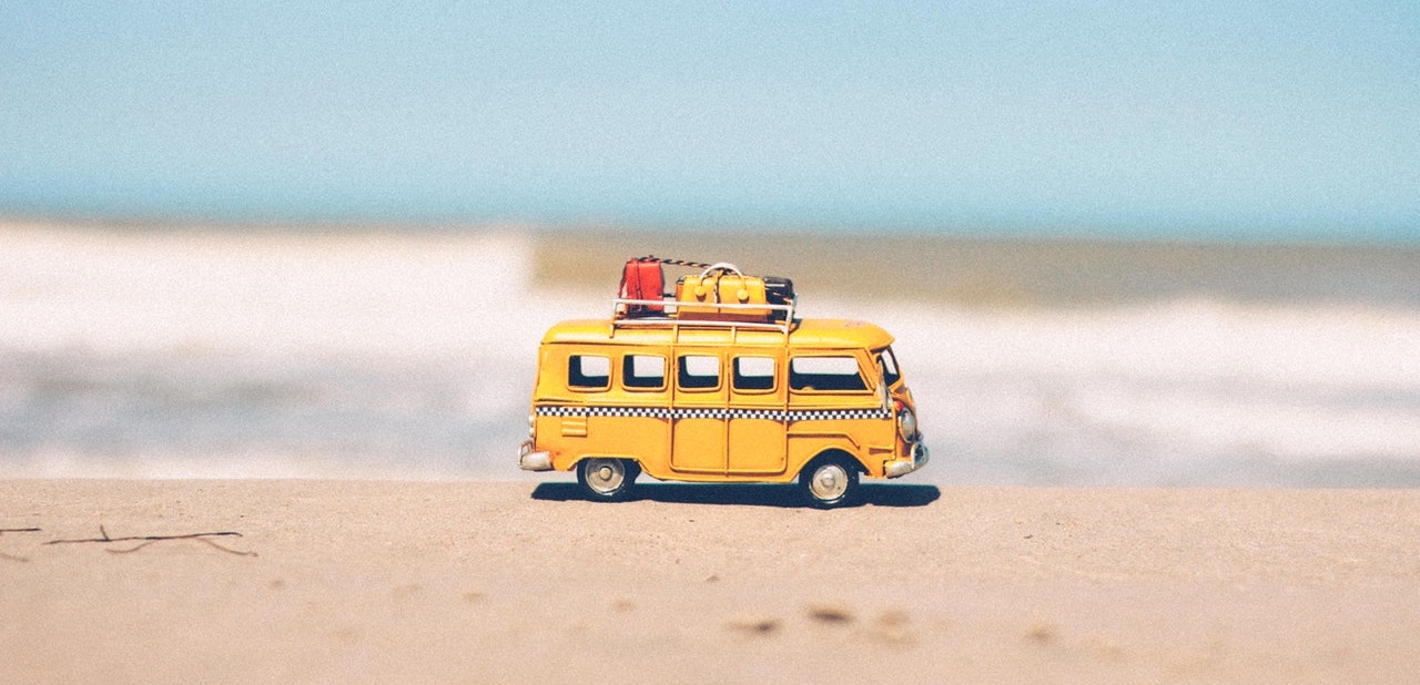 Photograph of a yellow toy camper van on a beach